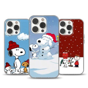 Puede incluir: Tres fundas para teléfono con Snoopy y los Peanuts en escenas invernales. Una funda muestra a Snoopy construyendo un muñeco de nieve, otra a Snoopy y Woodstock, y la tercera a Charlie Brown decorando un árbol de Navidad. Cada funda tiene un borde transparente.