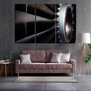 May include: A triptych canvas print showing a close-up of a turbine engine. The image highlights the detailed metal blades and circular parts, emphasising the industrial design and metallic textures. The colour scheme is mainly dark with shades of grey and brown.