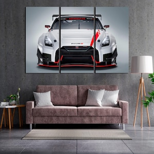 Könnte beinhalten: Dreiteiliger Leinwanddruck eines weißen und schwarzen Nissan GT-R Nismo Rennwagens mit roten Akzenten. Das Nismo-Logo ist sichtbar. Das Kunstwerk hängt über einem mauvefarbenen Sofa.