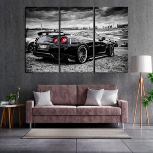 May include: Monochrome triptych canvas art depicting a black sports car on a race track. The car has red rear lights and is on grass. The background shows a cloudy sky and a race track.