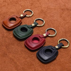 Puede incluir: Cuatro llaveros de cuero en marrón, verde, rojo y negro. Cada llavero tiene una abertura circular y un anillo de latón para sujetar las llaves. Los llaveros están hechos de cuero y tienen un diseño cosido.