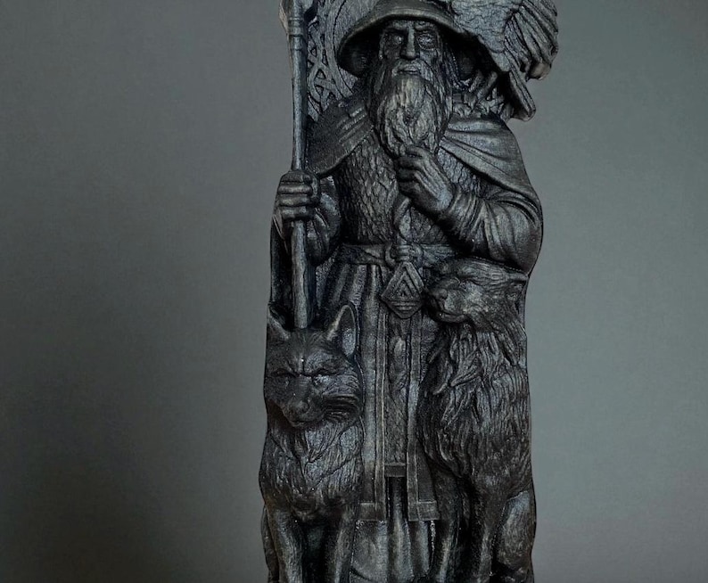 Peut inclure: Statue gris fonc&eacute; d'un homme barbu portant un chapeau et une cape, tenant un b&acirc;ton. Un aigle est perch&eacute; sur son &eacute;paule, avec un loup et un renard &agrave; ses pieds. La statue pr&eacute;sente des d&eacute;tails complexes.