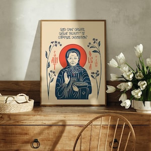 Puede incluir: Una l&aacute;mina rectangular sobre fondo crema con una ilustraci&oacute;n estilizada de una persona con pa&ntilde;uelo y halo rojo. El texto dice: GOD CAN CREATE GREAT BEAUTY OF COMPLETE DESOLATION. Tallos florales de color azul oscuro flanquean la figura central.