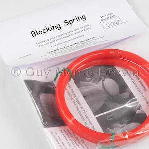 May include: A red blocking spring for use with a king and table on a pool table. The spring is 57 cm in diameter. The text on the packaging reads "Blocking Spring" and "Speed up your blocking and save in position for use with most types of crown tables".
