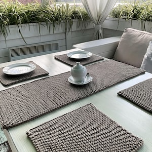 Puede incluir: Cuatro manteles individuales de punto marrón sobre una mesa blanca con un plato blanco y una pequeña jarra de crema blanca sobre uno de los manteles individuales.