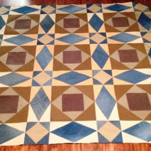 May include: A geometric patterned quilt with squares and diamonds in shades of blue, brown, and beige.