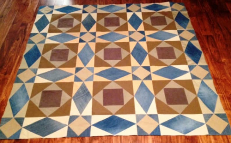 May include: A geometric patterned quilt with squares and diamonds in shades of blue, brown, and beige.