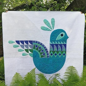 May include: A white quilt featuring a large, stylized bird applique in shades of teal, blue, and green. The bird has a geometric wing pattern and a crest. The quilt surface displays intricate linear quilting stitches. The text Purdy Bird is visible.
