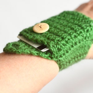 May include: A green crocheted wristlet with a wooden button and a credit card inside.