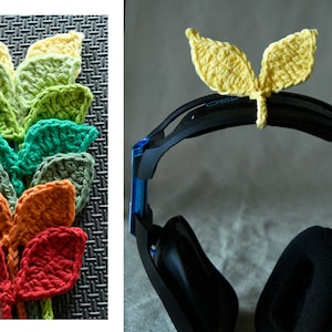 May include: A set of crocheted leaf-shaped charms in various colours, including yellow, green, orange, and red. The charms are attached to a black headset.