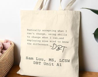 May include: Cream-colored tote bag with the text "Radically accepting what I can't change..." and "-DBT" in black. Below the text is "Sam Luu, MS, LCSW DBT Unit A1". The bag has a simple design and is made of a canvas material.