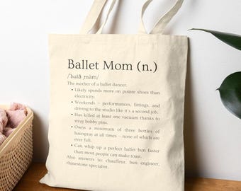 May include: Cream-colored tote bag with the text "Ballet Mom (n.)" and a definition. The definition describes a ballet dancer's mother, mentioning pointe shoes, performances, and hairspray.