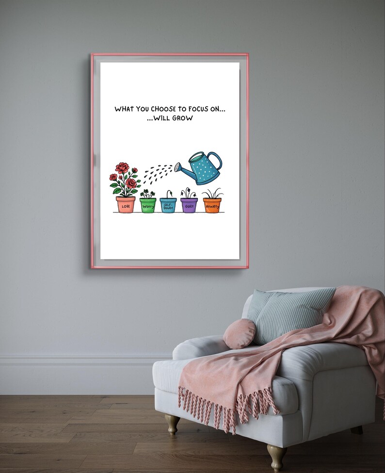 May include: A framed print with a pink border displays the text "WHAT YOU CHOOSE TO FOCUS ON... ...WILL GROW." Below, a watering can waters plants labeled "Love," "Worry," "Guilt," and "Anxiety." The print hangs above a white armchair.