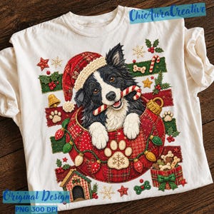 May include: A cream-colored t-shirt featuring a graphic of a black and white dog wearing a red plaid Santa hat, holding a candy cane in its mouth. The dog is inside a large red ornament surrounded by Christmas lights, paw prints, and gifts.