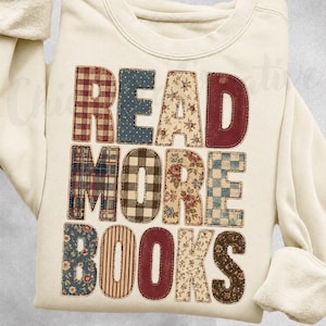 Peut inclure: Un sweat-shirt à col rond couleur crème avec le texte READ MORE BOOKS en grandes lettres majuscules. Chaque lettre est remplie d'un motif de tissu différent, incluant du vichy rouge, des pois bleus, des fleurs, du tartan et des rayures.