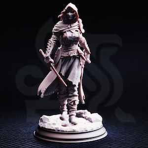Könnte beinhalten: Detaillierte Figur einer Kriegerin mit Kapuzenmantel und Maske, die ein Schwert hält. Die Figur befindet sich in einer dynamischen Pose mit komplizierten Rüstungs- und Kleidungsdetails. Der Sockel ist eine runde Plattform.