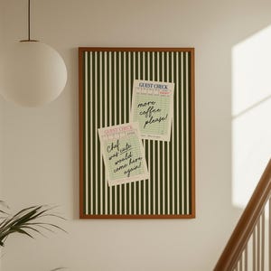Puede incluir: Una obra de arte enmarcada con un borde marrón y un patrón de rayas verticales verdes y blancas. Dos notas de control de invitados están sujetas a la obra de arte. Una dice "Chef was cute would come here again!" y la otra dice "more coffee please!"