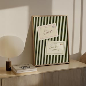 May include: A framed print with a green and white striped background. Two postcards are attached to the frame. The top postcard reads "PS. I love you" and the bottom postcard reads "Love You More!"