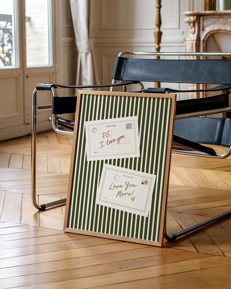 May include: A framed bulletin board with a green and white striped pattern. Two postcards are pinned to the board. The top postcard reads "PS I love you" and the bottom postcard reads "Love You More!"