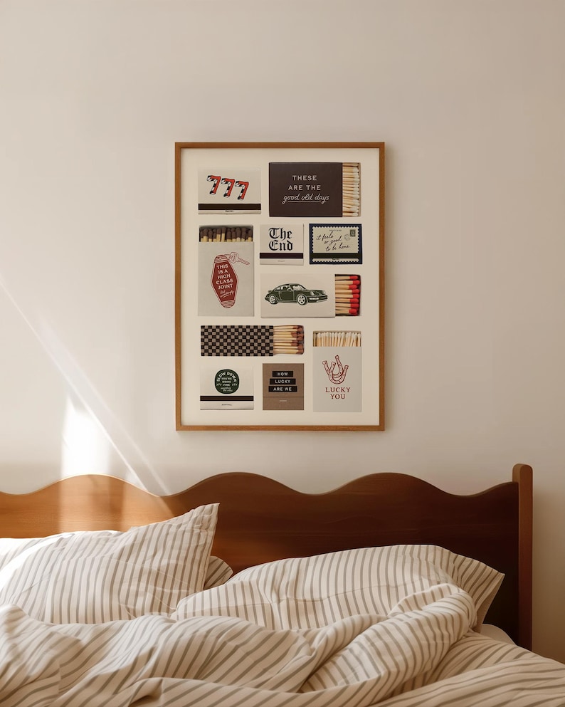 May include: A framed artwork featuring various matchbox designs. The designs include the number 777, text that reads "There are the good old days", a green car, and the words "Lucky You". The artwork hangs above a bed.