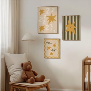 Puede incluir: Tres impresiones art&iacute;sticas enmarcadas con un tema de guarder&iacute;a. Las impresiones presentan estrellas amarillas y el texto "Good Night Sleep Tight". Una impresi&oacute;n tiene un fondo a rayas verdes y blancas. Un oso de peluche marr&oacute;n est&aacute; sentado en una silla de madera.