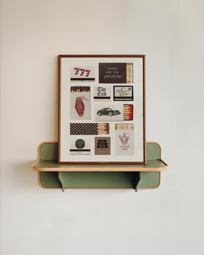 May include: A framed art piece featuring various matchbox designs with text like "777", "The End", and "Lucky You". The artwork is displayed on a green and wood-toned shelf, creating a vintage aesthetic.