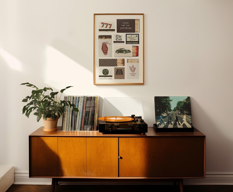 May include: A mid-century modern wooden cabinet with a record player, vinyl records, and a framed collage of vintage matchbooks. A potted plant sits on top. The album cover of The Beatles' Abbey Road is visible.