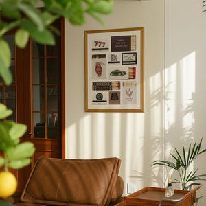 May include: A framed artwork featuring various vintage-style images, including a hotel key tag, a classic car, and matchboxes with text. The artwork is displayed on a light-colored wall, with a brown leather sofa and a wooden serving cart in the foreground.