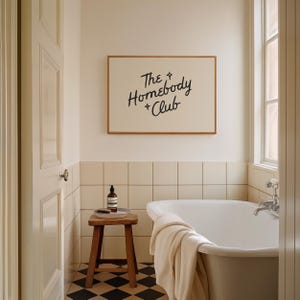 May include: A bathroom scene featuring a white bathtub, a wooden stool, and a framed sign that reads "The Homebody Club." The room has a neutral color palette with black and white checkered flooring and a window.