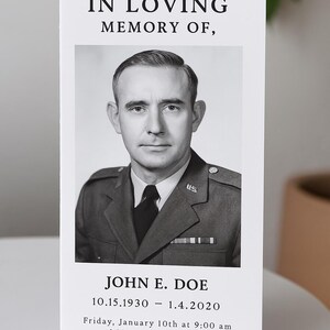 May include: Black and white photo of a man in a military uniform. The photo is on a white card with the text "IN LOVING MEMORY OF, JOHN E. DOE 10.15.1930 - 1.4.2020 Friday, January 10th at 9:00 am 1 Memorial Avenue, Arlington, Virginia 22211"