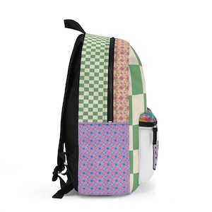 May include: A colorful backpack with a patchwork design. The bag features a mix of patterns, including green and cream checkerboard, floral, and blue geometric prints. It has a black back and straps, a side pocket, and a white tag with black text.