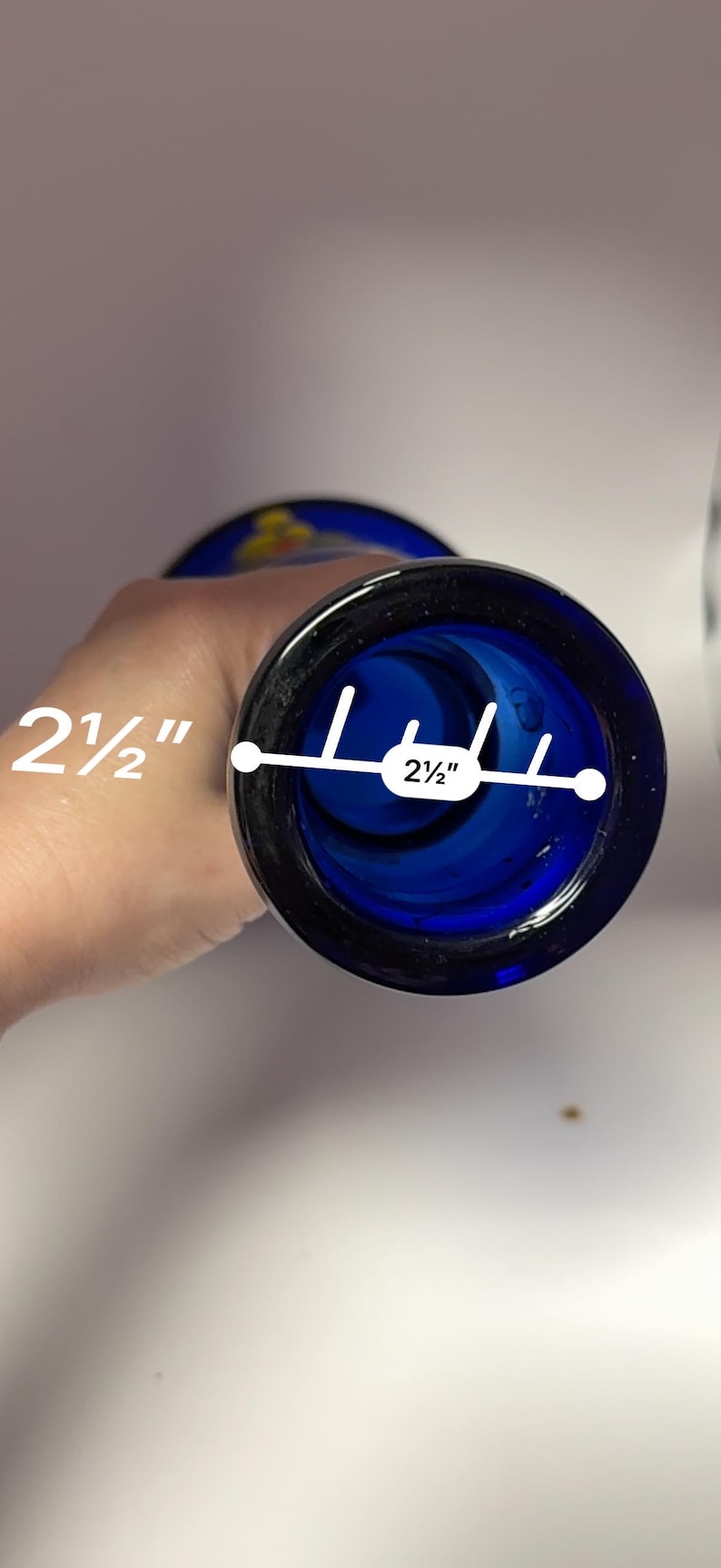 May include: A cobalt blue glass vase with a 2.5-inch opening. The vase has a dark blue rim and a slightly flared shape. The interior is a deep blue color, and the vase appears to be handmade.