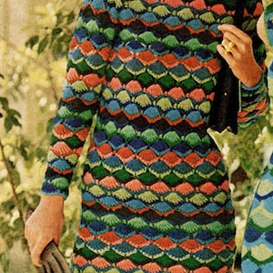 May include: A woman wearing a long-sleeved, multi-colored crochet dress with a geometric pattern. The dress has a scalloped hem and is paired with red shoes.