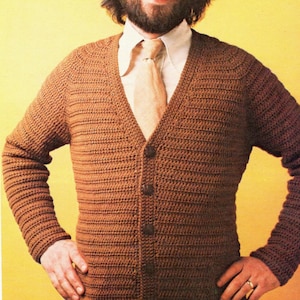 May include: A brown crocheted cardigan with a v-neck and button closure. The cardigan is worn over a white collared shirt with a brown tie.