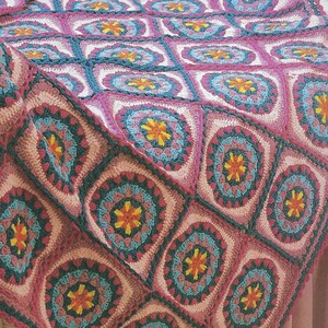 May include: A crocheted blanket with a repeating pattern of colorful flowers in shades of pink, blue, and yellow. The blanket is made with a variety of stitches and textures, creating a visually interesting and tactile experience.