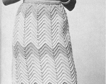 Peut inclure: Une photo en noir et blanc d'une femme portant une jupe en crochet avec un motif en chevron. Elle porte un pull à col roulé et a les cheveux longs.
