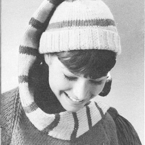 Puede incluir: Un gorro de punto a rayas con un borde largo doblado hacia abajo. El gorro es blanco con rayas marrones.