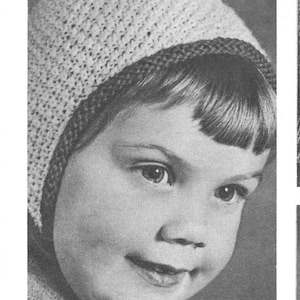 May include: A black and white photograph of a young child wearing a knitted hat with a pointed top. The hat is light-coloured with a dark trim and a striped tip. The child is looking to the side.