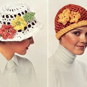 May include: Two women wearing crocheted hats. The hat on the left is white with yellow, red, and green flowers. The hat on the right is red and orange with yellow flowers.