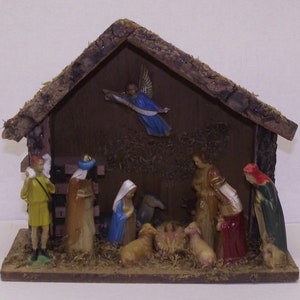 May include: A wooden nativity scene with a brown roof and a manger with a baby Jesus, Mary, Joseph, and an angel. There are also three wise men and a shepherd in the scene.