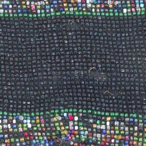 May include: A close-up of a black beaded bag with a colorful beaded design. The bag is made of small, round beads that are sewn together in a pattern. The beads are in various colors, including red, green, blue, and white.