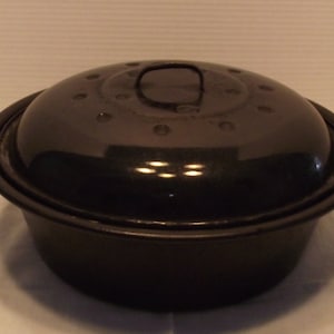 May include: Black enameled cast iron pot with a lid. The pot has a round shape and a black handle on the lid.