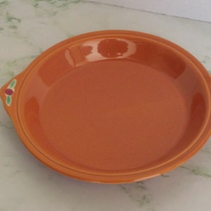 May include: Orange ceramic pie plate with green and red floral accents on the handles.