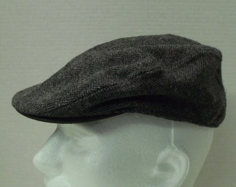 May include: A gray herringbone tweed newsboy cap with a black leather brim.