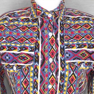 May include: A long-sleeved button-up shirt with a colourful geometric pattern in shades of blue, red, yellow, black and white.