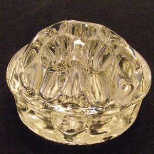 May include: A clear glass flower frog with a textured surface and multiple openings for holding stems.