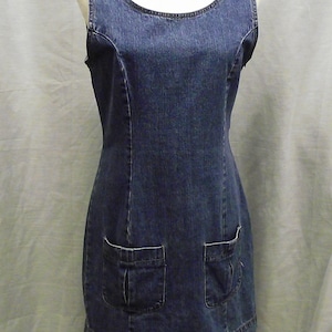 Può includere: Un abito in denim senza maniche con scollo rotondo e due grandi tasche sul davanti.