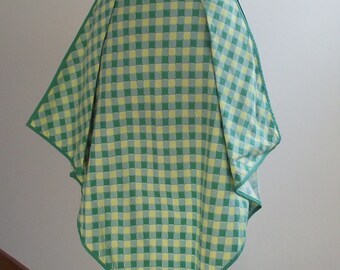 Pode incluir: Um avental de vichy verde e amarelo com uma bainha pontiaguda. O avental é plissado e tem uma cintura larga.