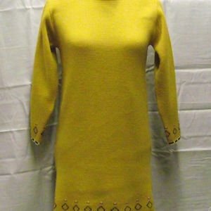 Può includere: Un abito in maglia giallo a maniche lunghe con un bordo bianco e nero intorno al collo e all'orlo.