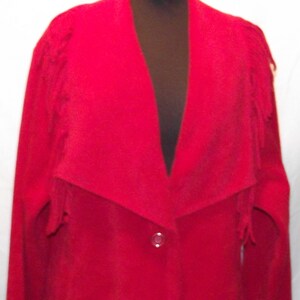 May include: A long red coat with a shawl collar and fringe detail. The coat has a single button closure.